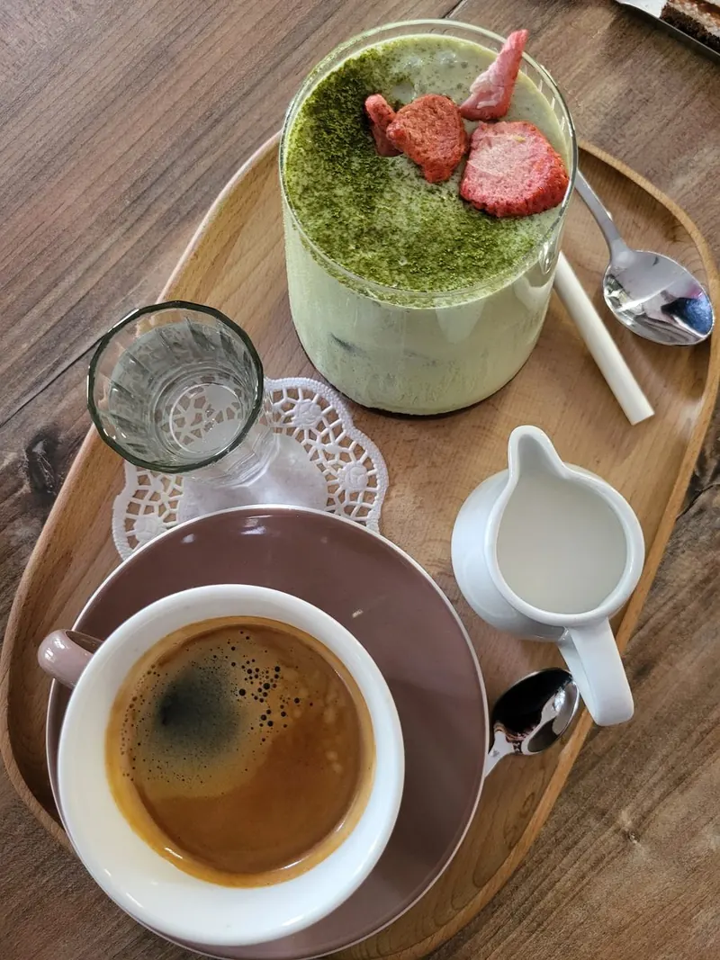 Matcha latte s jahodami a espresso s mliekom na drevenom podnose