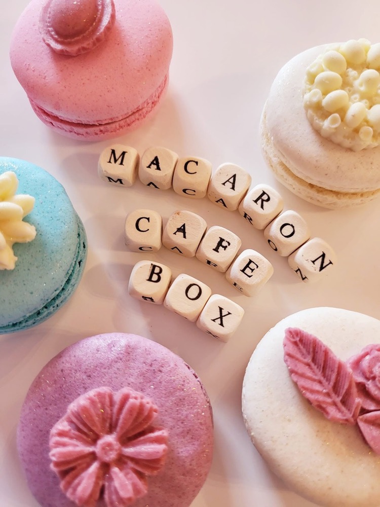 Farebné makrónky okolo drevených kociek s nápisom Macaron cafe box