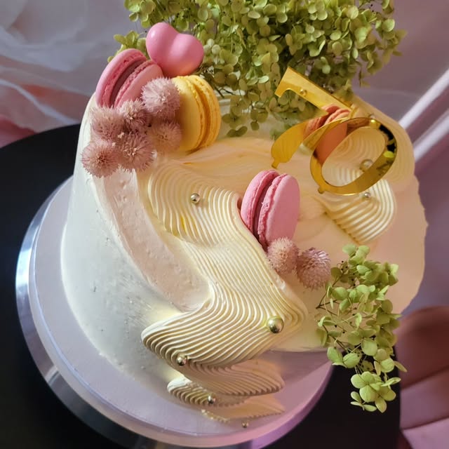 Biela torta zdobená makrónkami a kvetmi