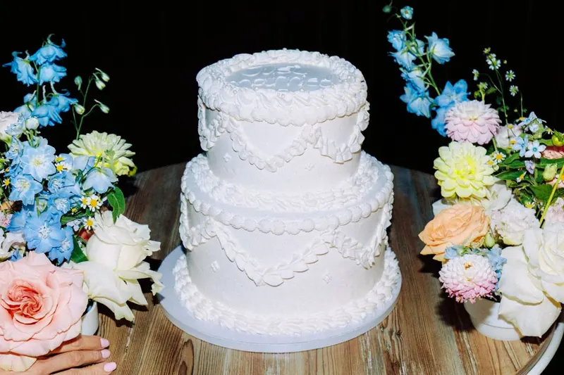 Dvojposchodová svadobná torta obklopená kvetmi