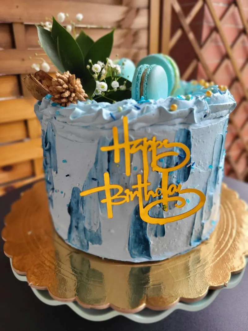 Modrá torta s makrónkami a zlatým nápisom Happy Birthday